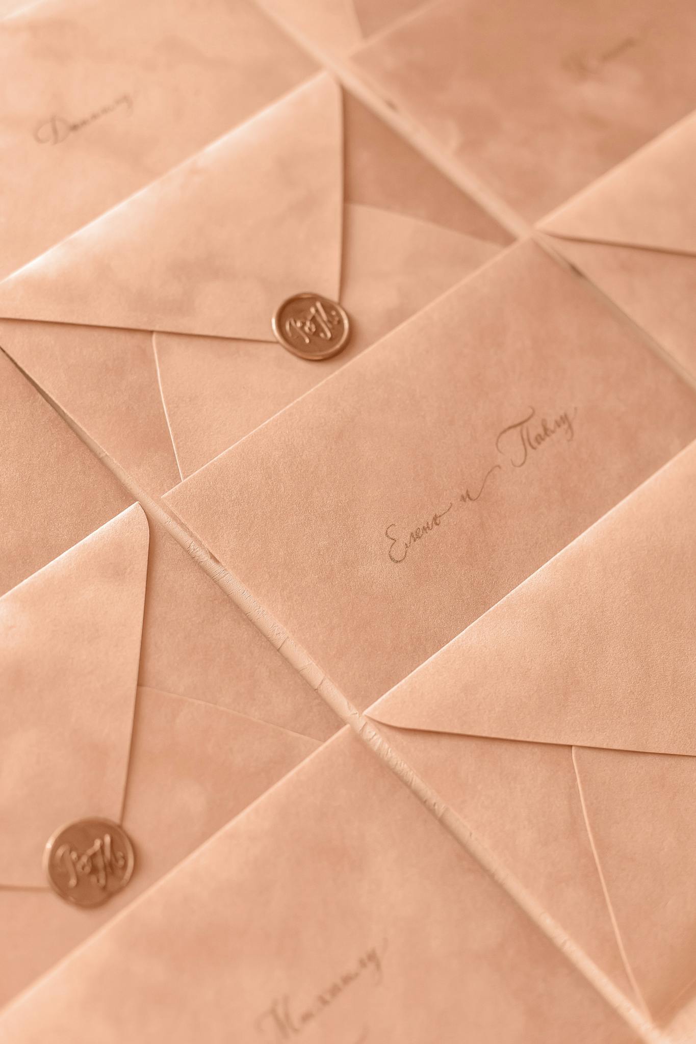 A collection of elegant wedding invitation envelopes with wax seals in a soft, warm tone.