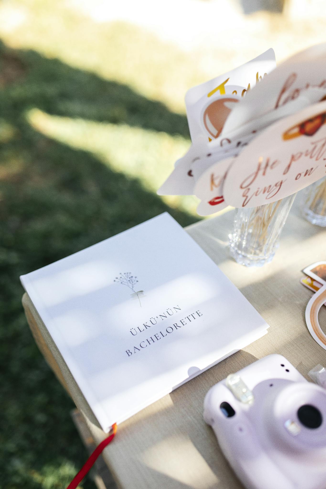 Close-up of bachelorette party decorations with instant camera on outdoor table.