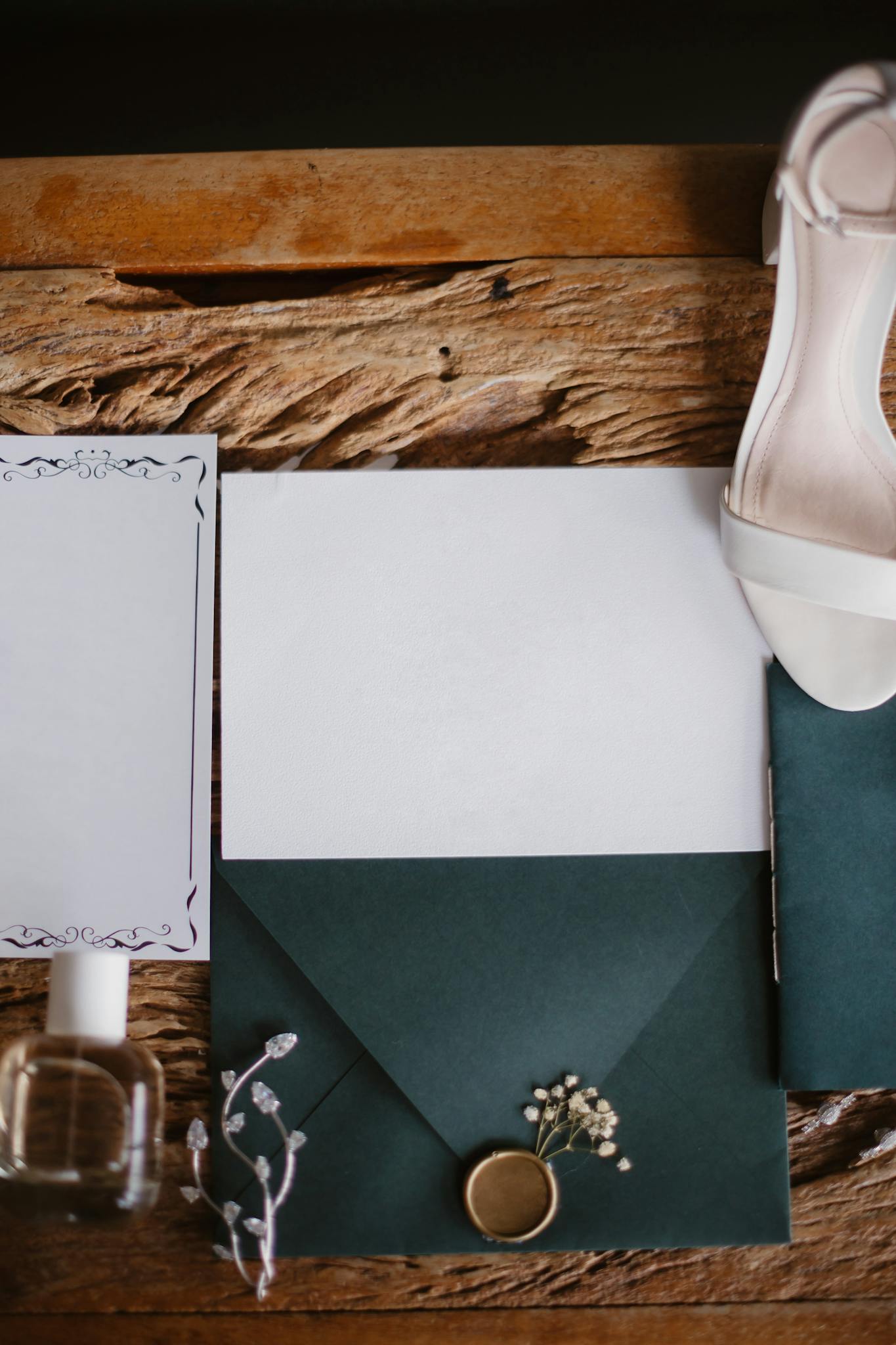 Flat lay of a wedding invitation set with a white shoe on a rustic wooden background.